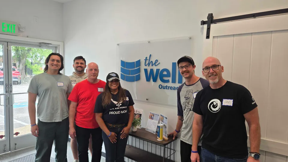Team members beside The Well Outreach sign